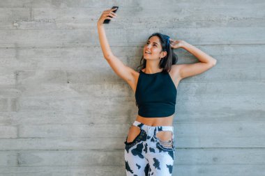 Genç bir kadın cep telefonuyla selfie çekiyor.