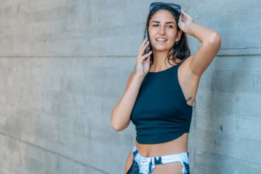 Arka plan duvarı ve yeri olan cep telefonuyla konuşan kadın