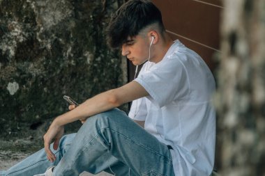 Cep telefonu ve kaykayı olan genç bir çocuk.