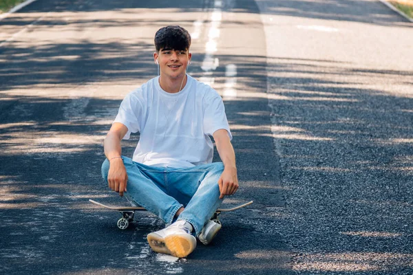 Kaykaylı ve kulaklıklı çocuk yolda.