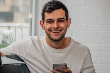 Evde cep telefonu kullanan genç adam.