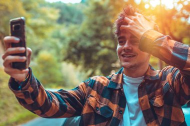 Genç adam dışarıda cep telefonuyla fotoğraf çekiyor.