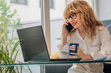 Cep telefonu ve bilgisayarı olan bir kadın.