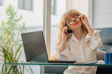 Dizüstü bilgisayarı ve cep telefonu olan bir kadın.