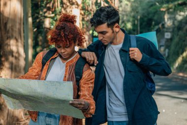 Haritaları ve sırt çantaları olan çok ırklı genç bir çift.