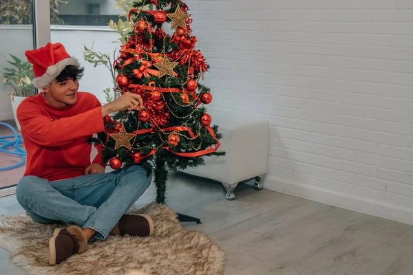 Teenage Boy Decorating Christmas Tree Home Santa Claus Hat — Stock Photo, Image