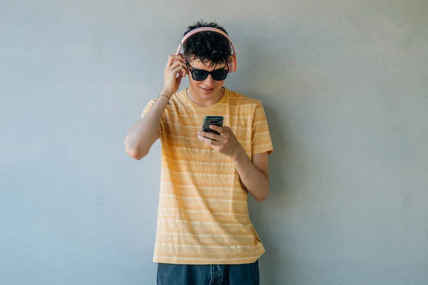 Tiener Jongen Met Koptelefoon Mobiele Telefoon Muur — Stockfoto