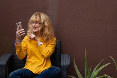 Kadın cep telefonuyla video konferansında konuşuyor.