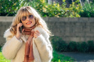 Ceketli kadın cep telefonuyla konuşuyor.