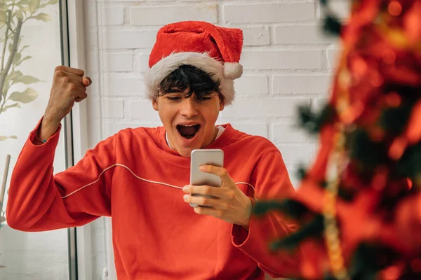 年轻而兴奋的年轻人拿着手机在家里庆祝圣诞节 — 图库照片