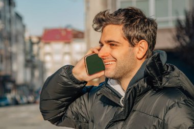 Sokakta cep telefonu olan gülümseyen bir adam.