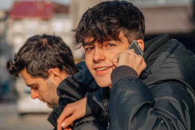 Sokakta telefonu olan genç çocuklar.