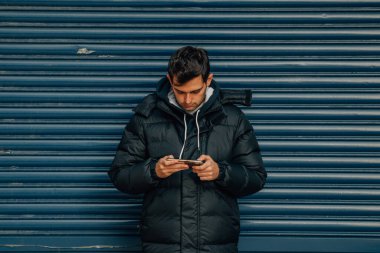 Sokaktaki ceketli ve cep telefonlu adam.