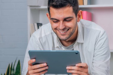 Evde dijital tableti ya da bilgisayarı olan genç adam