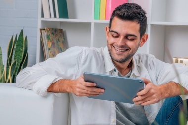 Evde dijital tableti ya da bilgisayarı olan genç adam