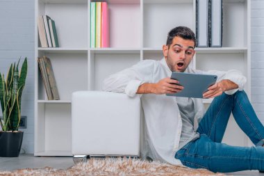 Evde dijital tableti ya da bilgisayarı olan genç adam