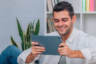 Evde dijital tableti ya da bilgisayarı olan genç adam
