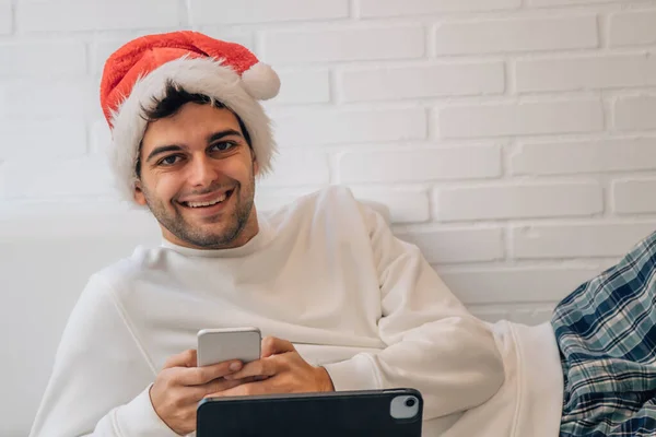 クリスマスに携帯電話とパソコンを持って家にいる男は — ストック写真