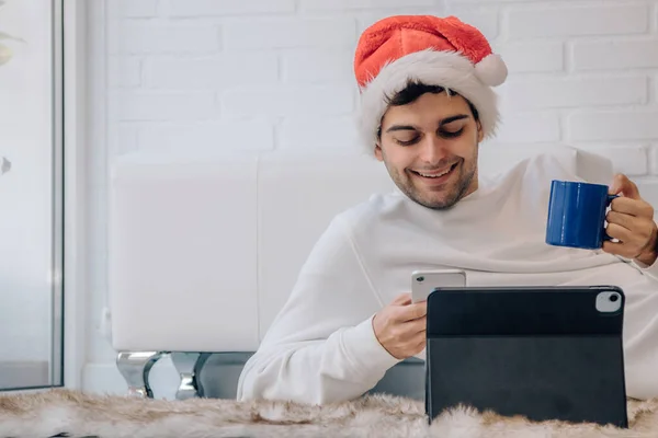 Мужчина Шляпе Санта Клауса Дома Мобильным Телефоном Компьютером — стоковое фото