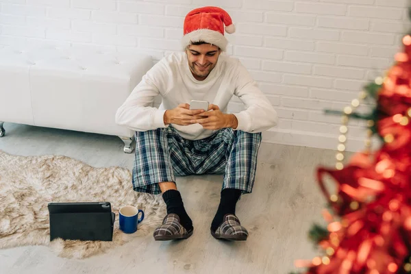 Мужчина Шляпе Санта Клауса Дома Мобильным Телефоном Компьютером — стоковое фото