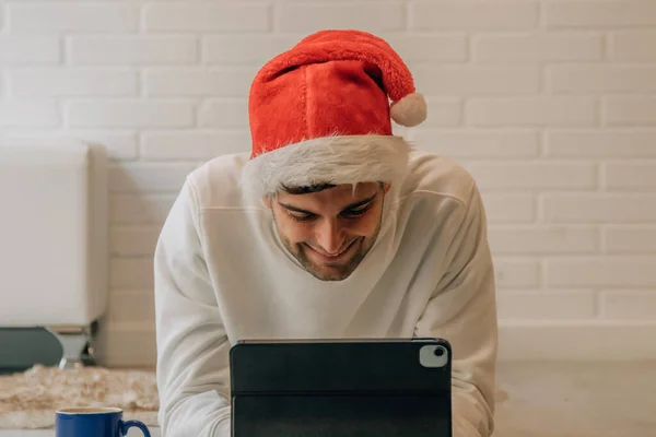圣诞节的时候 家里拿着圣诞帽和电脑的男人 — 图库照片