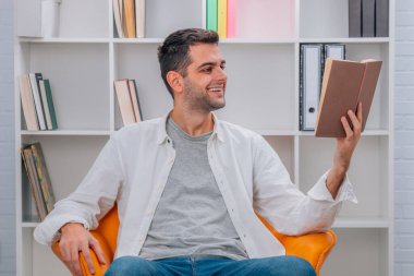 Evde ders kitabı okuyan bir adam var.