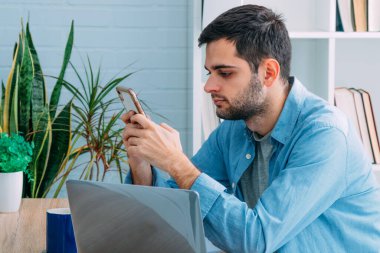 Cep telefonu ve bilgisayarı olan adam evde.