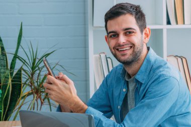 Cep telefonu ve bilgisayarı olan adam evde.