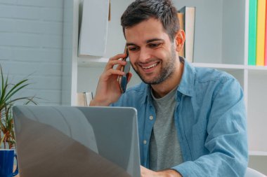 Cep telefonu ve bilgisayarı olan adam evde.