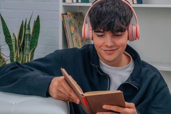 Νεαρός Άνδρας Στο Σπίτι Διαβάζοντας Βιβλίο Και Ακούγοντας Μουσική Ακουστικά — Φωτογραφία Αρχείου