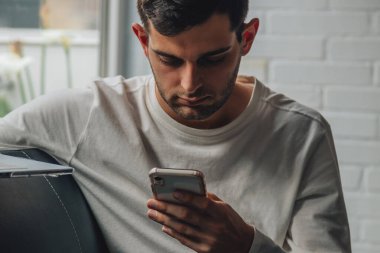 Evdeki adam cep telefonuna bakıyor.