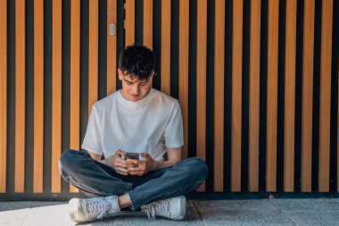 Sokakta cep telefonu olan genç bir çocuk.