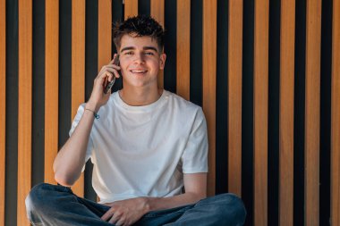 Sokakta cep telefonu olan genç bir çocuk.