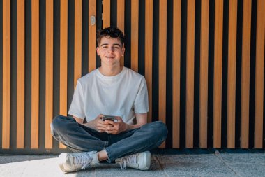 Sokakta cep telefonu olan genç bir çocuk.