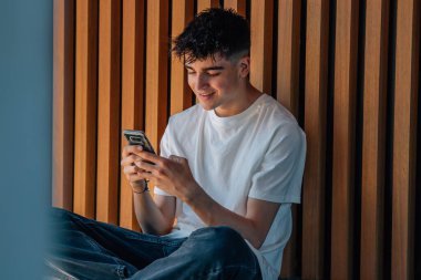 Sokakta cep telefonu olan genç bir çocuk.