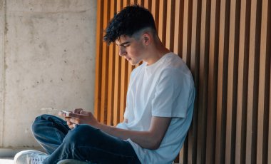 Sokakta cep telefonu olan genç bir çocuk.