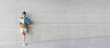 Üniversitede ya da kampüste sırt çantası ve kitap taşıyan genç bir öğrenci