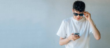 Güneş gözlüklü ve cep telefonlu genç kız.