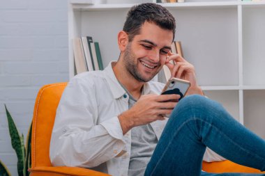 Evde cep telefonuna bakan çekici bir adam.