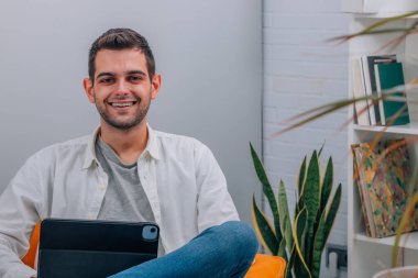 Evde bilgisayar ya da tabletle çekici bir adam var.