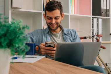 Adam evde dizüstü bilgisayar ve cep telefonu, cep telefonu veya akıllı telefon ile çalışıyor.