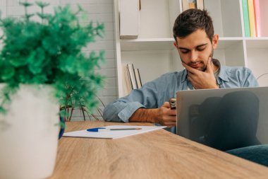 Evde bilgisayar, cep telefonu ya da akıllı telefonu olan genç bir adam