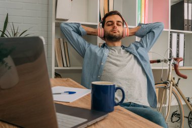 Evde kulaklıkla müzik dinleyen rahat bir adam.