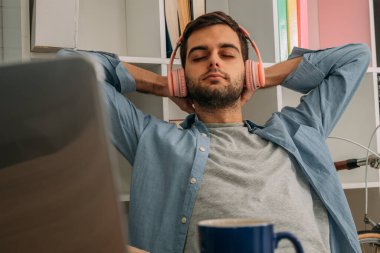 Evde kulaklıkla müzik dinleyen rahat bir adam.