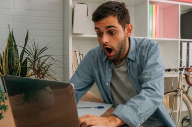 Evde bilgisayarlı ve şaşırmış bir adam var.