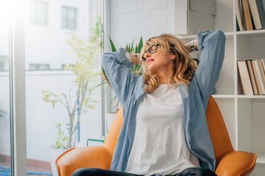 Rahatlamış bir kadın evinde dinleniyor.