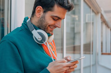 Sokaktaki genç adam cep telefonu ve kulaklığı ile