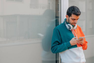 Şehir caddesinde cep telefonu olan genç bir adam.