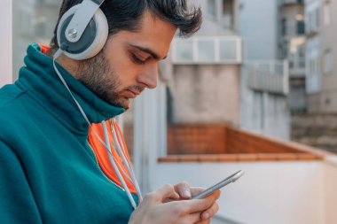 Sokaktaki genç adam cep telefonu ve kulaklığı ile