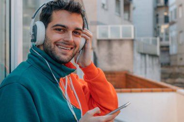 young man with mobile phone and headphones on the street